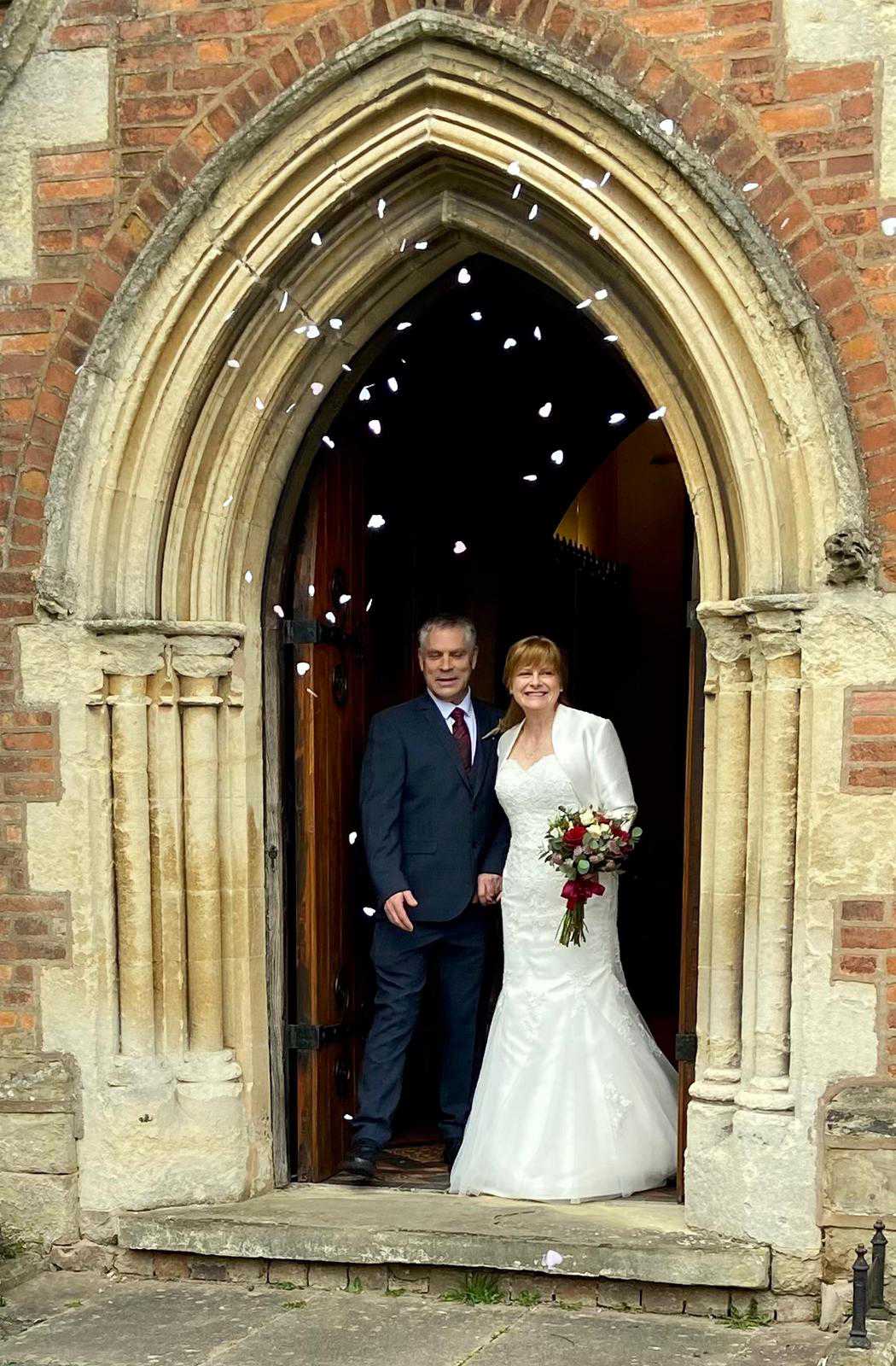 Photo of Jo and Tim coming out of St James church.